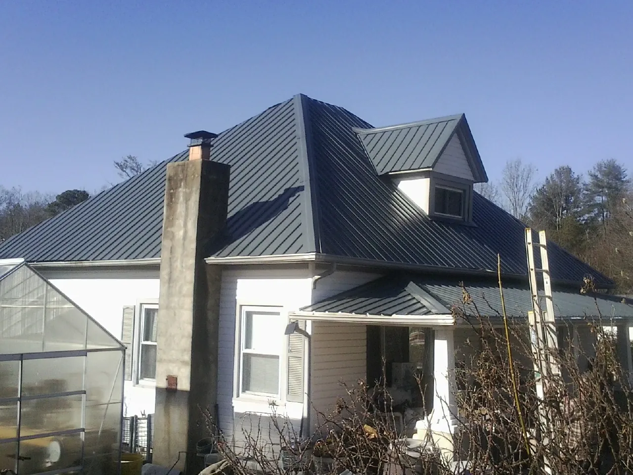 Dark blue standing seam metal roof on a white farmhouse with dormer — Slate & Tile Roof Repair by Roofing Brothers in Leicester