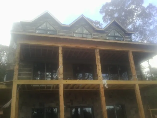 Dormers and porch framing on a large log home under construction — Roof Coating work by our crew in Leicester